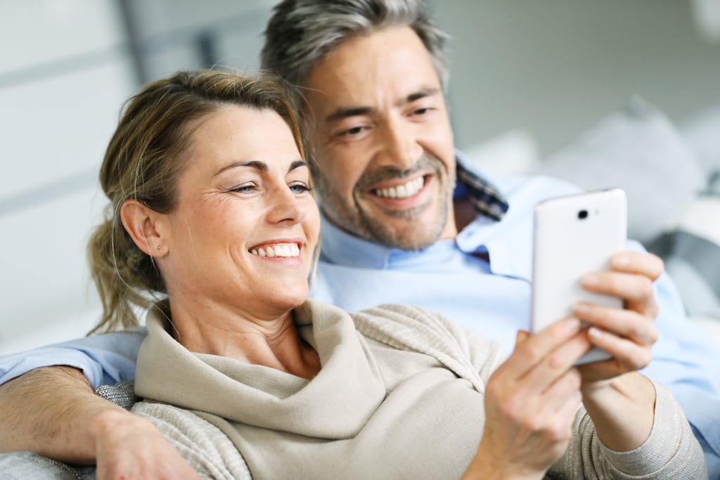 Lachendes Paar sieht zusammen auf ein Smartphone